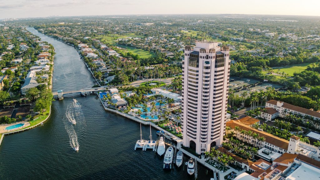 An aerial view of a tall building beside a canal with boats and houses