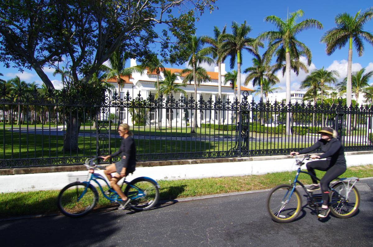 Cyclists ride in front of Flagler Museum