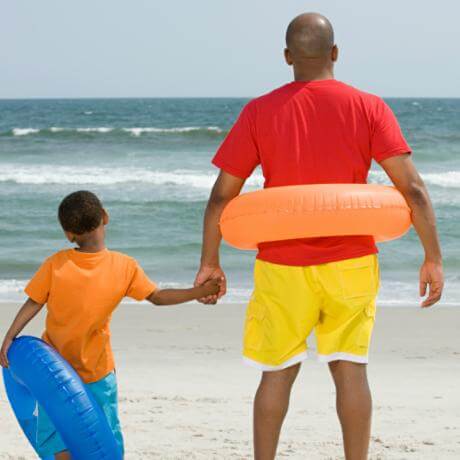 Father and son on beach with inner tubes