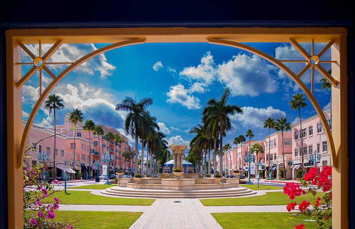 Outdoor plaza with pink buildings and palm treest at Mizner Park