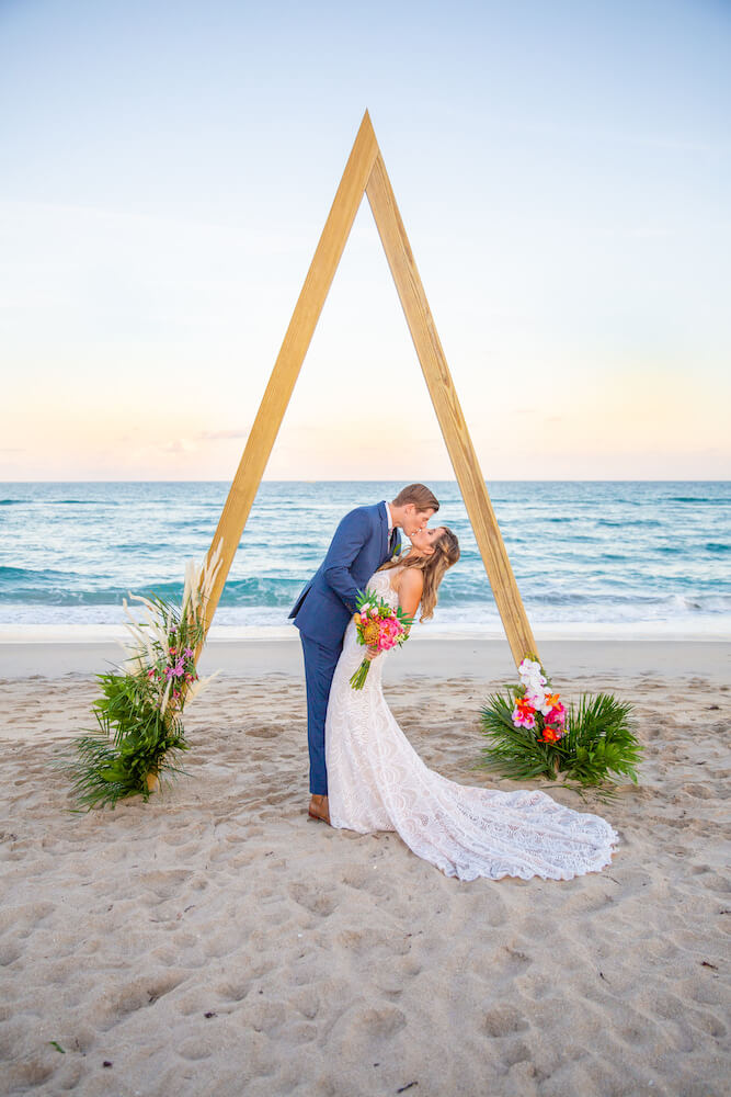 Bride and groom kissing in front of the ocean on the beach