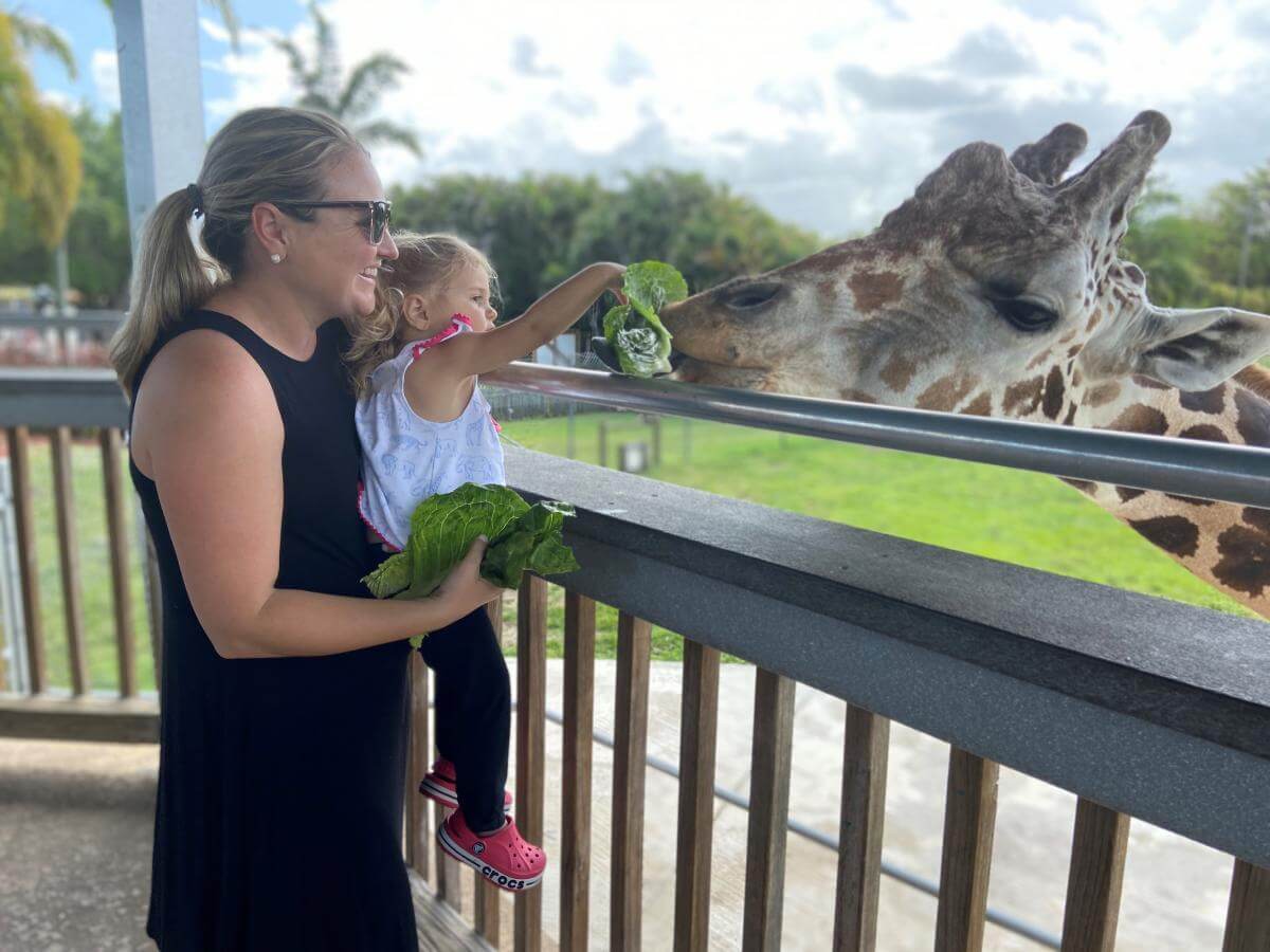 Mother and daughter feeding a giraffe.