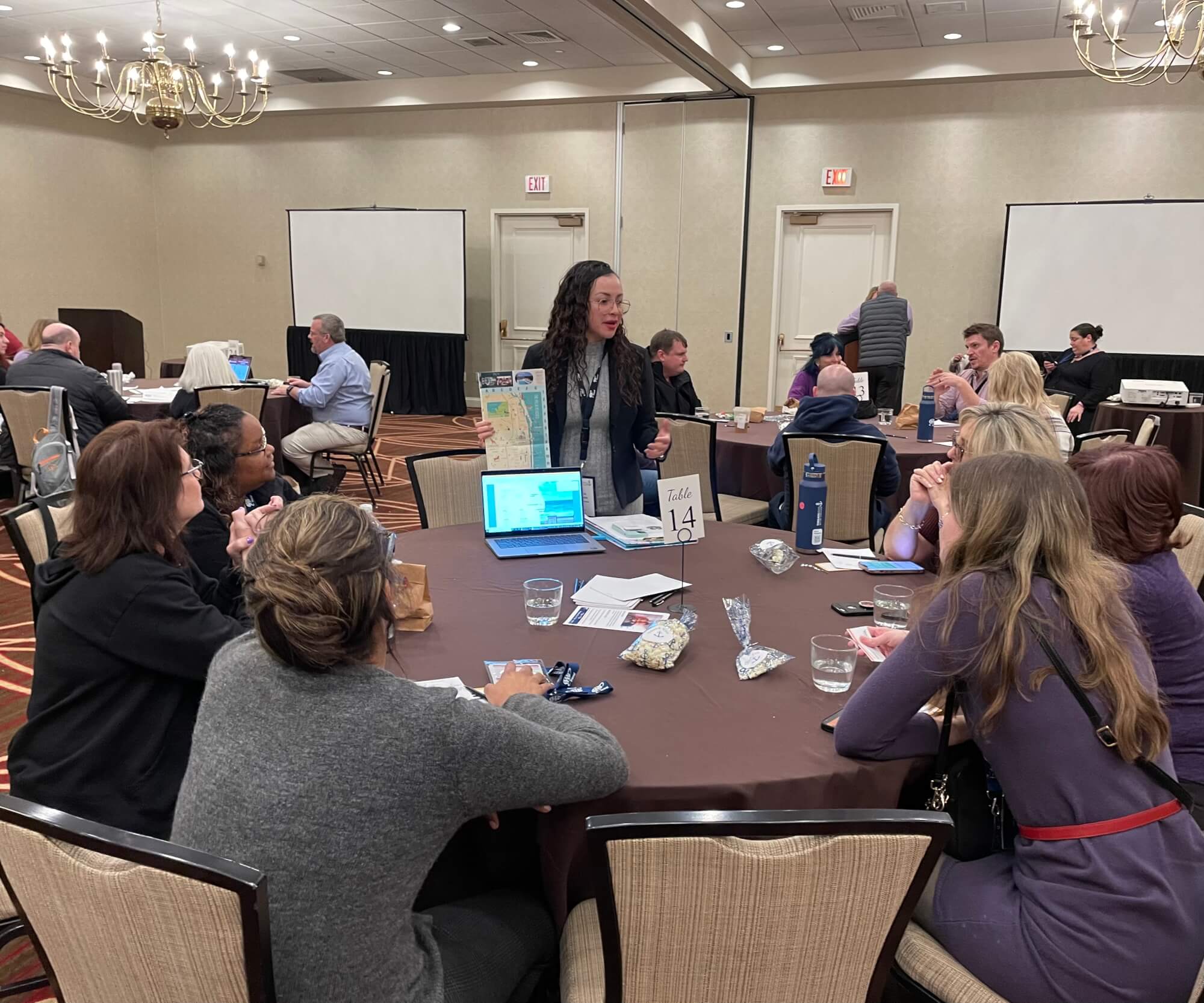 A woman presents a map to a group of people at a conference table