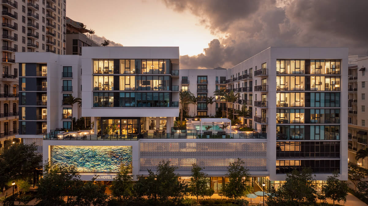 A modern hotel building with illuminated windows at sunset under a cloudy sky