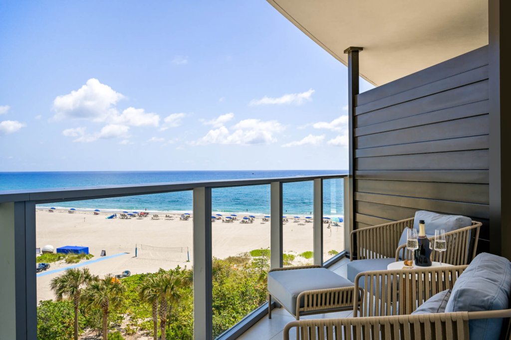 Uma varanda luxuosa com uma vista deslumbrante para o mar, com assentos confortáveis e uma mesa com taças de vinho