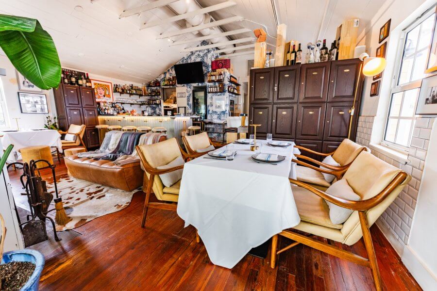 A cozy restaurant interior with wooden floors, leather couches, and a bar area
