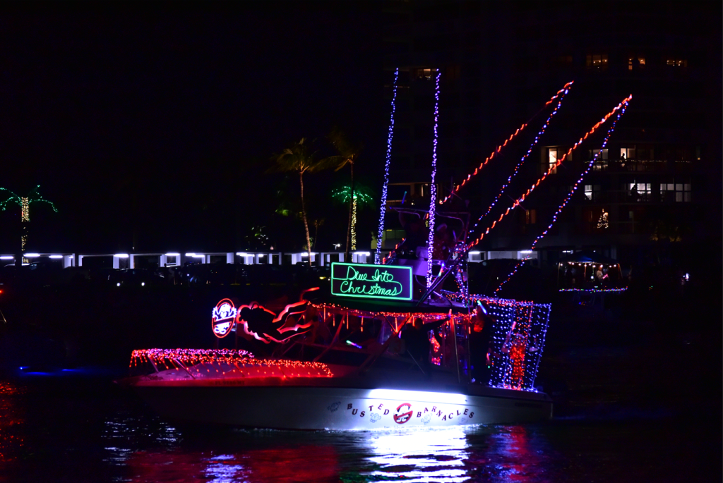 Un barco festivo decorado con luces navideñas y un cartel de "Sumérgete en la Navidad