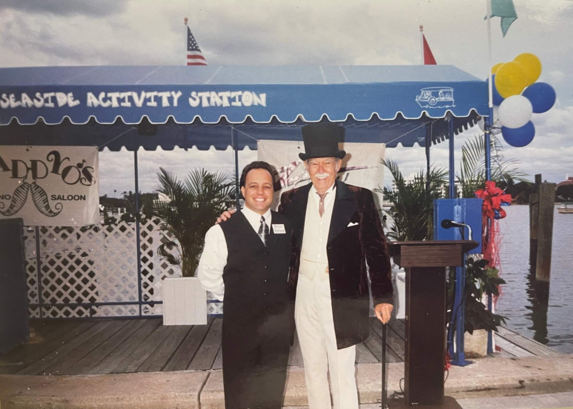 A man in a suit and a man in a top hat posing together outdoors