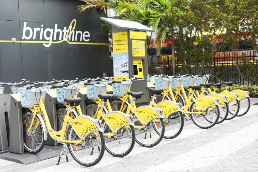 A row of bright yellow Brightline bicycles lined up at a docking station