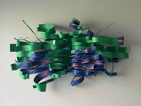 Abstract sculpture of intertwined green, blue, and orange ribbons