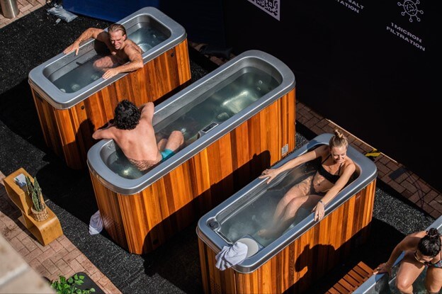 Four people relax in wooden hot tubs on a rooftop patio