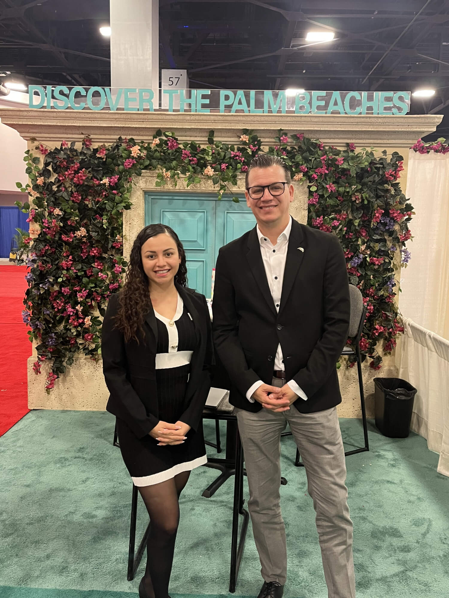 A man and a woman standing in front of a floral display at a conference
