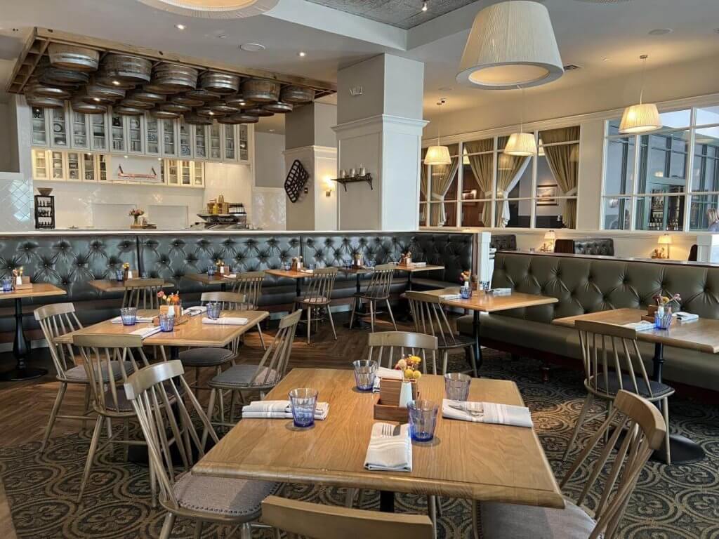 Ein gemütliches Restaurant mit Holztischen, Lederkabinen und einer rustikalen Weinfassdecke