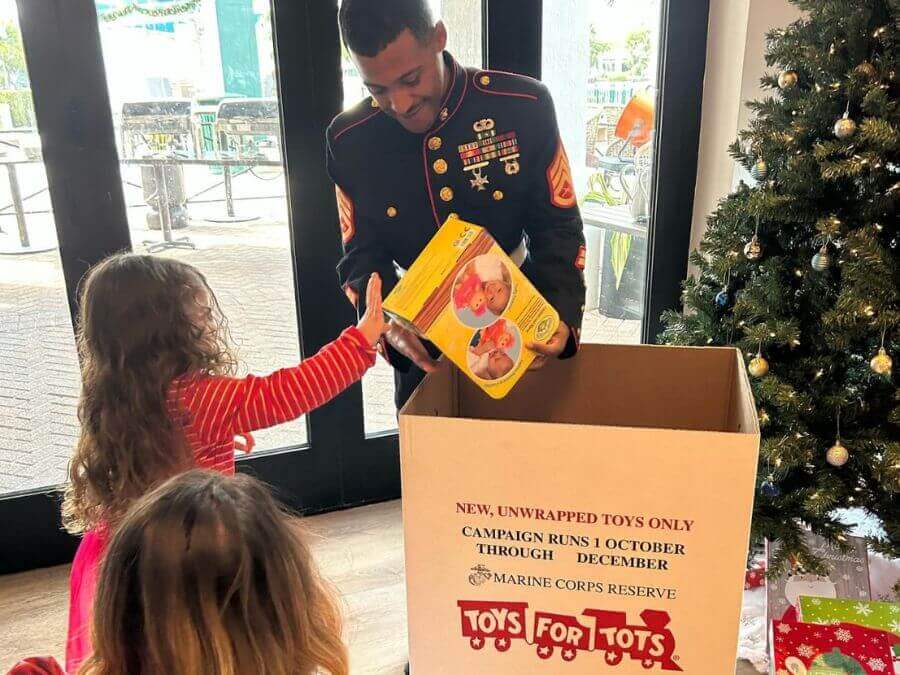 A Marine in uniform hands out toys to children during a holiday charity event