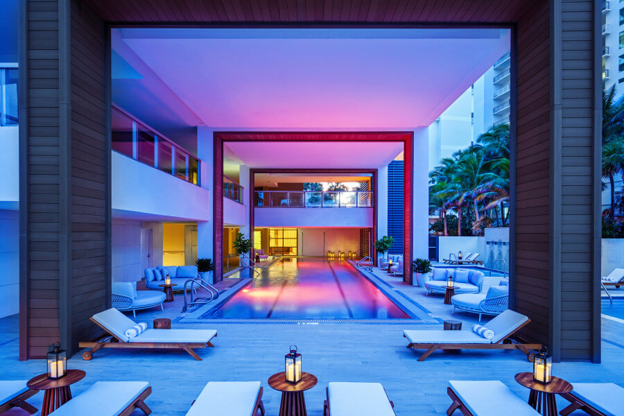 uma piscina com espreguiçadeiras e uma mesa em frente a ela