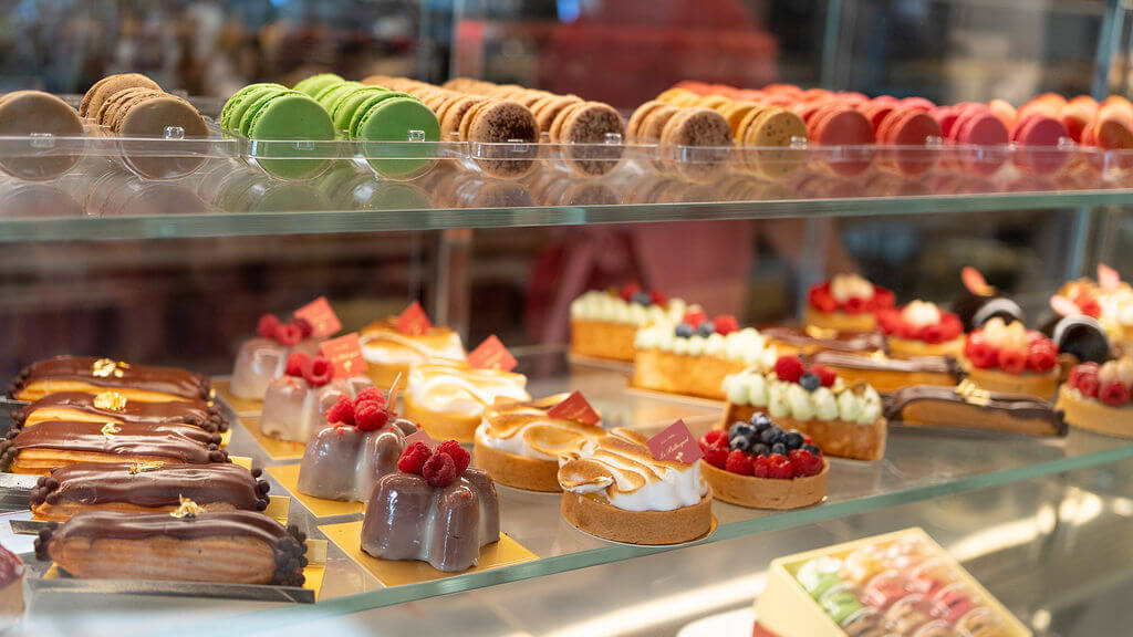 Une vitrine remplie d'un assortiment de pâtisseries, de macarons et de desserts colorés et décorés de manière complexe.
