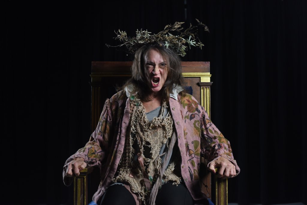 a woman sitting in a chair with a crown of leaves on her head
