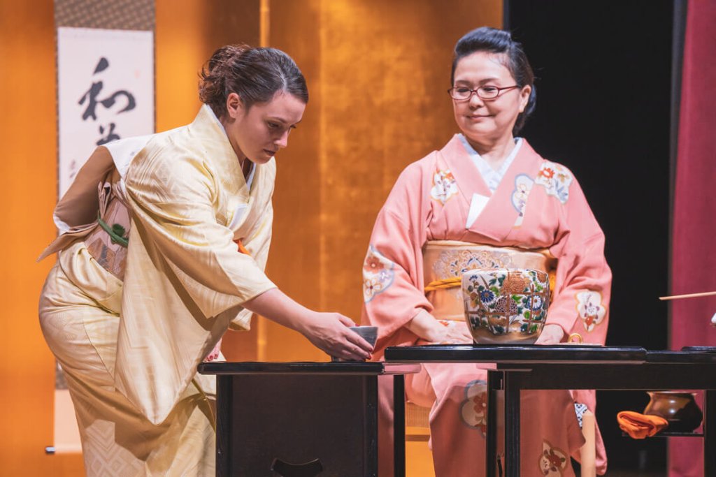 Deux femmes vêtues de kimonos japonais traditionnels se livrent à une cérémonie du thé, l'une servant et l'autre recevant une tasse de thé.