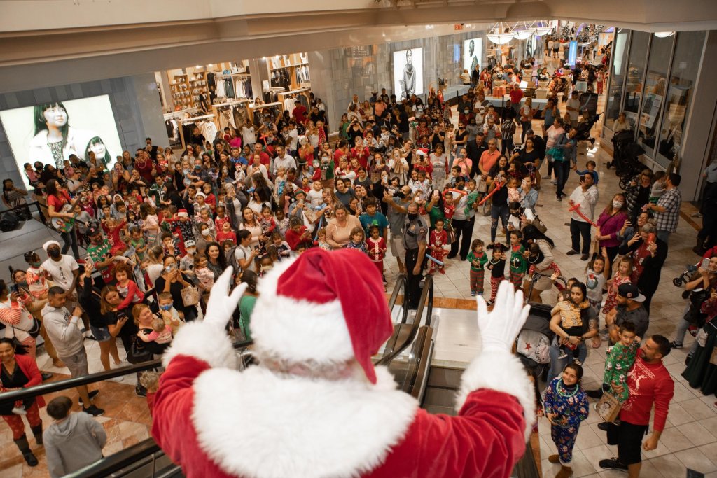 Der Weihnachtsmann kommt eine Rolltreppe in einem Einkaufszentrum herunter