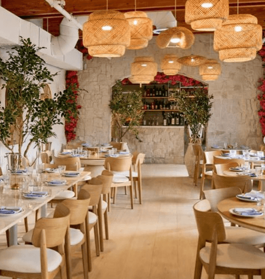 A rustic restaurant interior with wooden tables, chairs, and hanging bamboo light fixtures