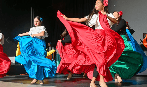 Jovens mulheres com saias coloridas apresentam uma dança folclórica tradicional no palco