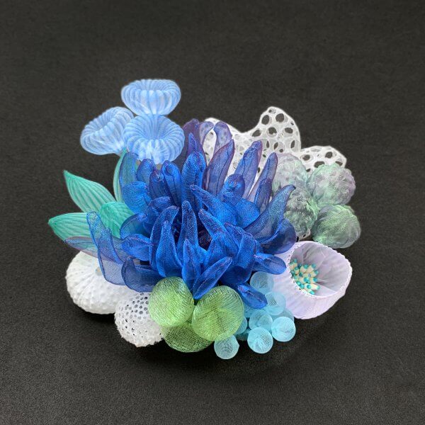 Intricate glass sculpture resembling a vibrant underwater coral reef with blue, green, and white hues