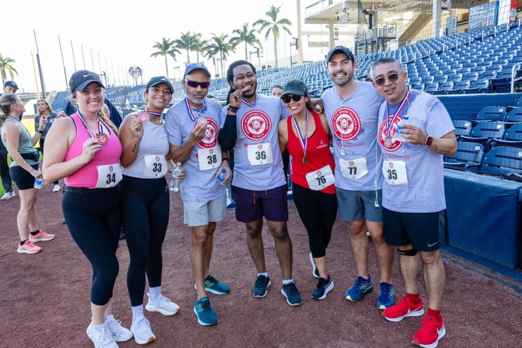Sete pessoas sorrindo e mostrando suas medalhas após uma corrida no CACTI Park of The Palm Beaches
