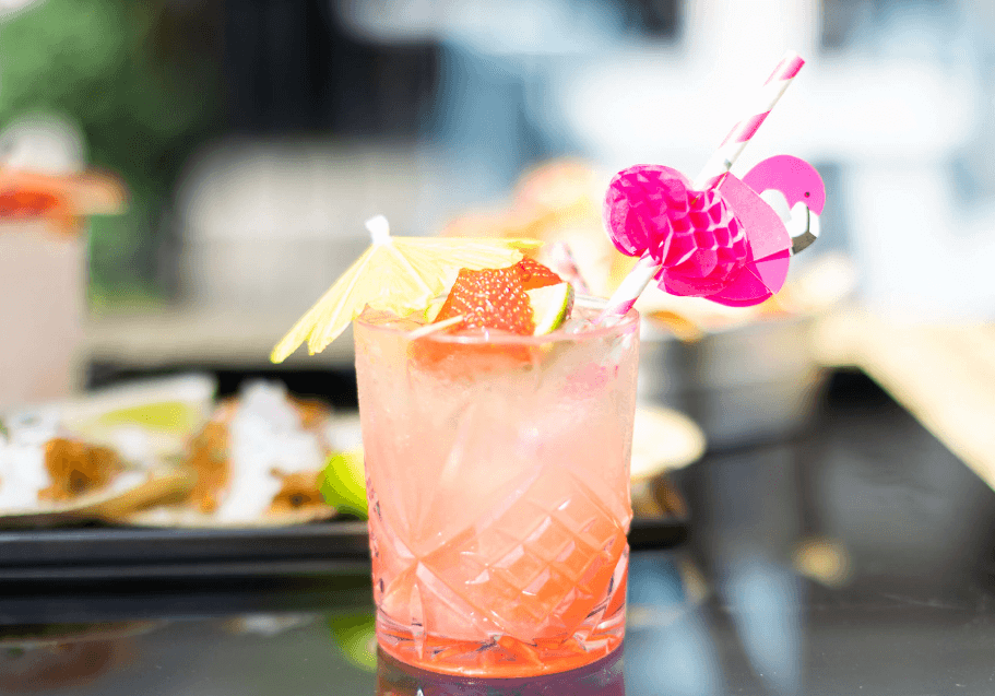 Cocktail with flowers and umbrella with a pink peach color