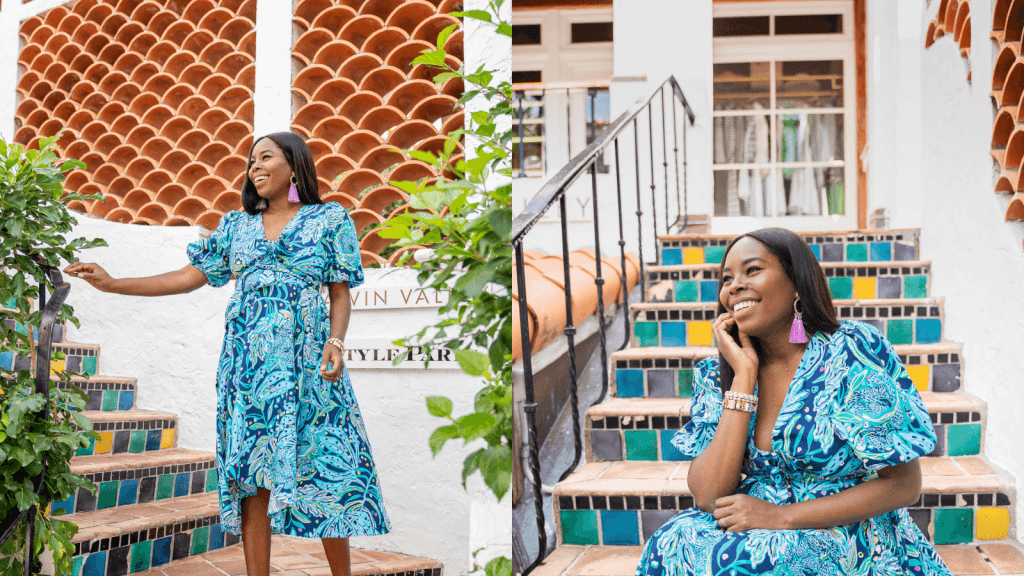 A woman in a vibrant blue floral dress sits on colorful tiled steps, smiling and posing for the camera