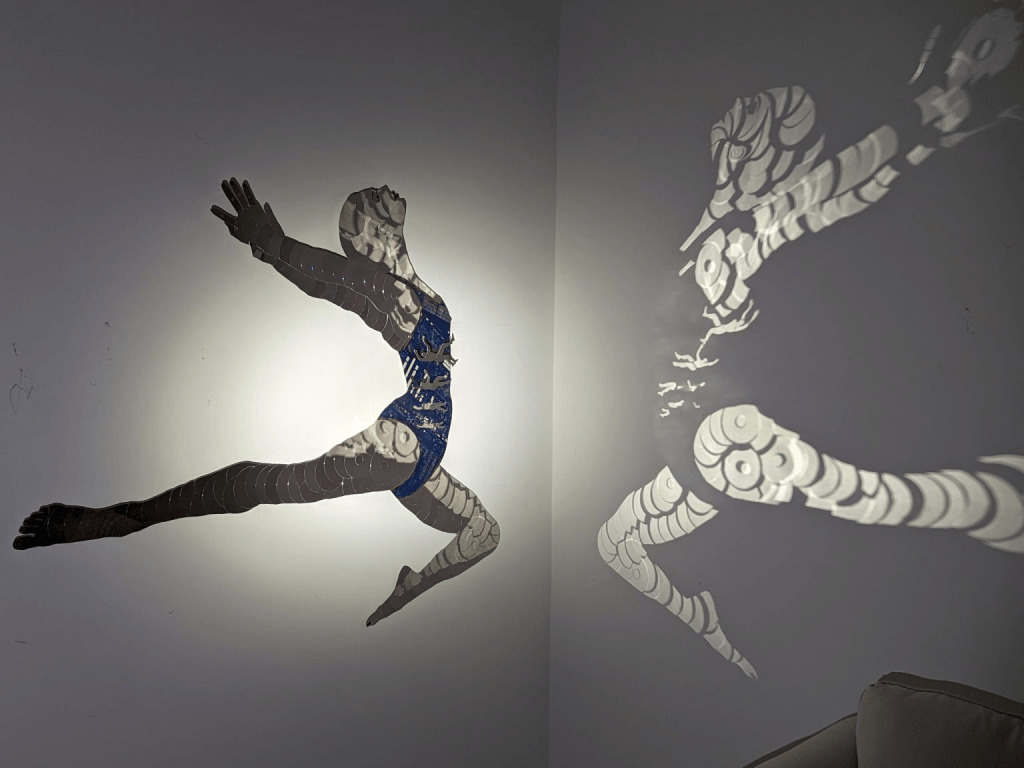 A striking wall art installation featuring a silhouette of a woman in a dynamic pose, with intricate patterns and shadows creating a mesmerizing visual effect