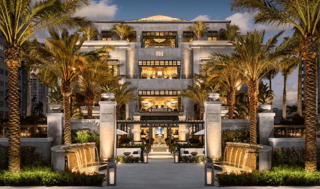 A luxurious hotel with a grand entrance flanked by palm trees and illuminated by warm lighting