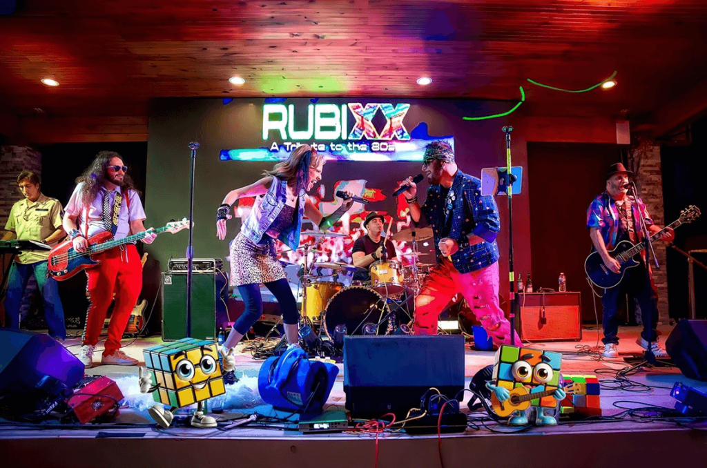 RubiXXX, una banda llena de energía inspirada en los años 80, actúa en el escenario con trajes coloridos, cubos de Rubik y pasos de baile llenos de energía