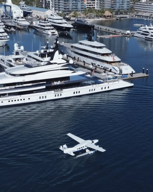 A bustling marina filled with luxury yachts and a small plane taking off from the water