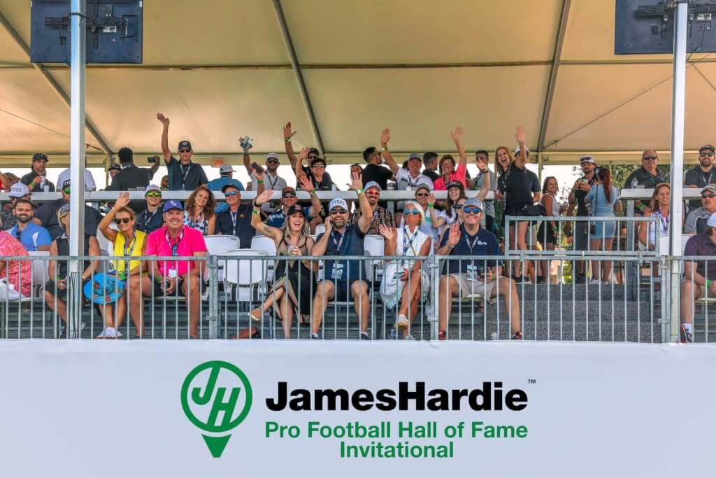 Eine lebhafte Menge jubelt unter einem großen Zelt beim JamesHardie Pro Football Hall of Fame Invitational