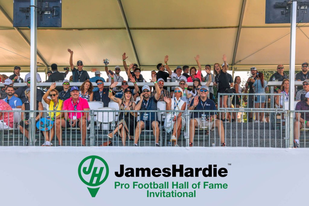 eine Gruppe von Menschen, die auf einer Bank beim James Hardie Pro Football Hall of Fame Invitational sitzen