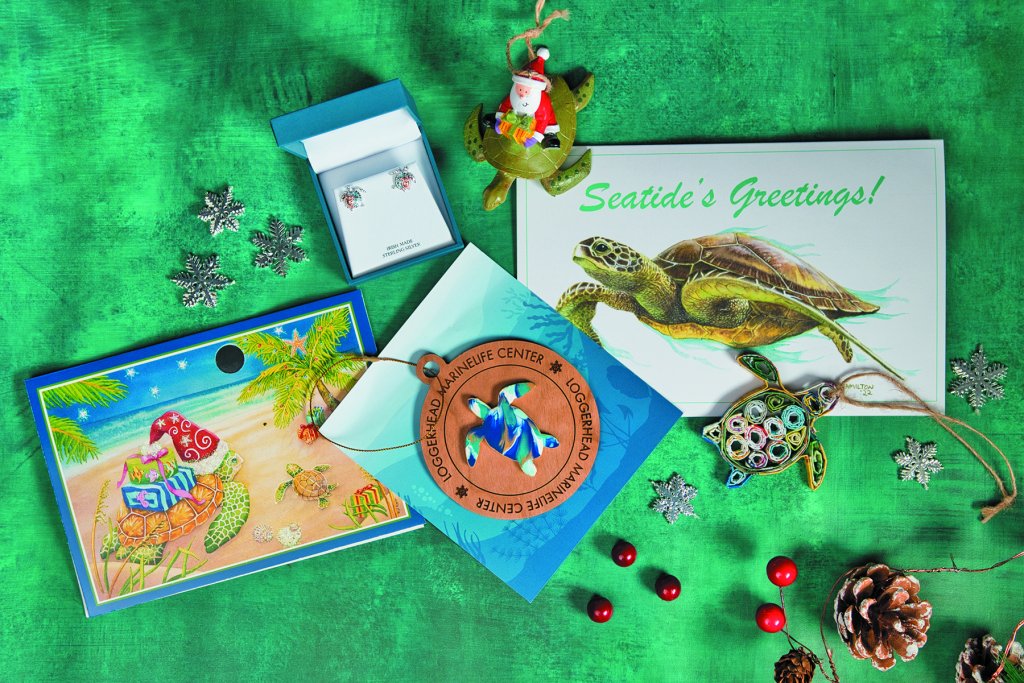 Ein Flatlay zum Thema Weihnachten mit von Meeresschildkröten inspirierten Geschenken, darunter Grußkarten, Ornamente, Schmuck und dekorative Elemente, arrangiert auf einem leuchtend grünen Hintergrund