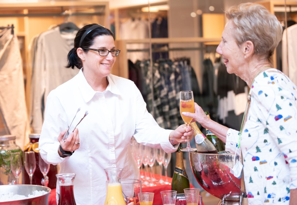 Une dame tend un mimosa à une autre dame au centre commercial de Wellington Green.