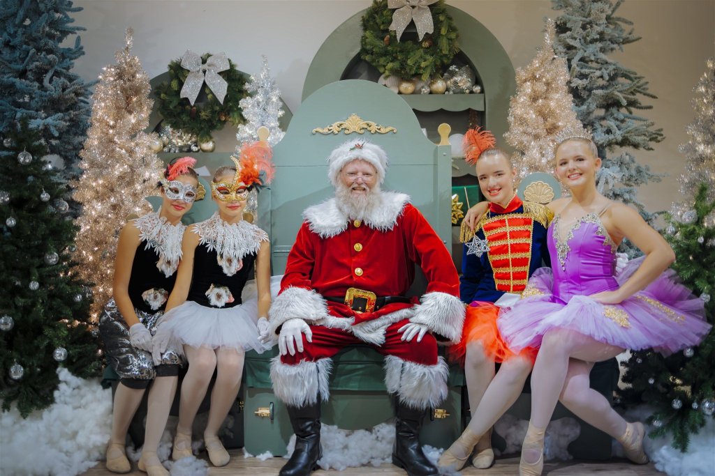 Der Weihnachtsmann sitzt umgeben von Tänzern in festlichen Kostümen inmitten einer weihnachtlichen Kulisse im CityPlace