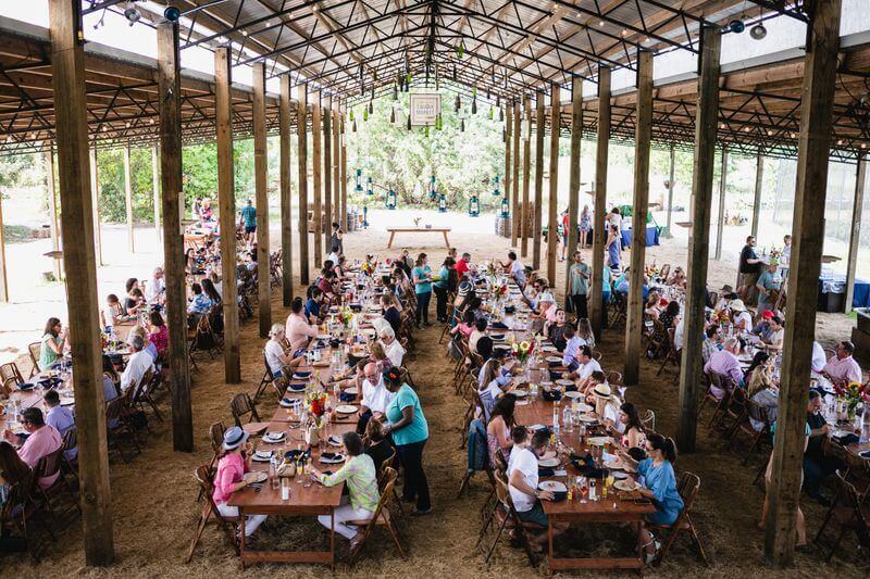 un groupe de personnes assises à des tables dans une grange couverte