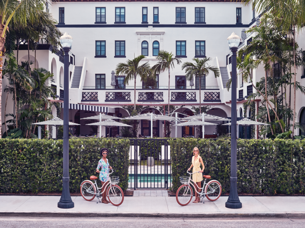zwei Mädchen mit Fahrrädern stehen vor dem weißen Elefanten in Palm Beach